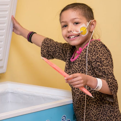 girl grabbing a freezer pop out of a chest freezer