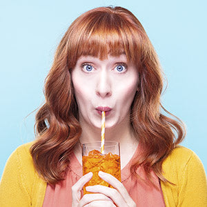 woman sipping from an orange powdered drink